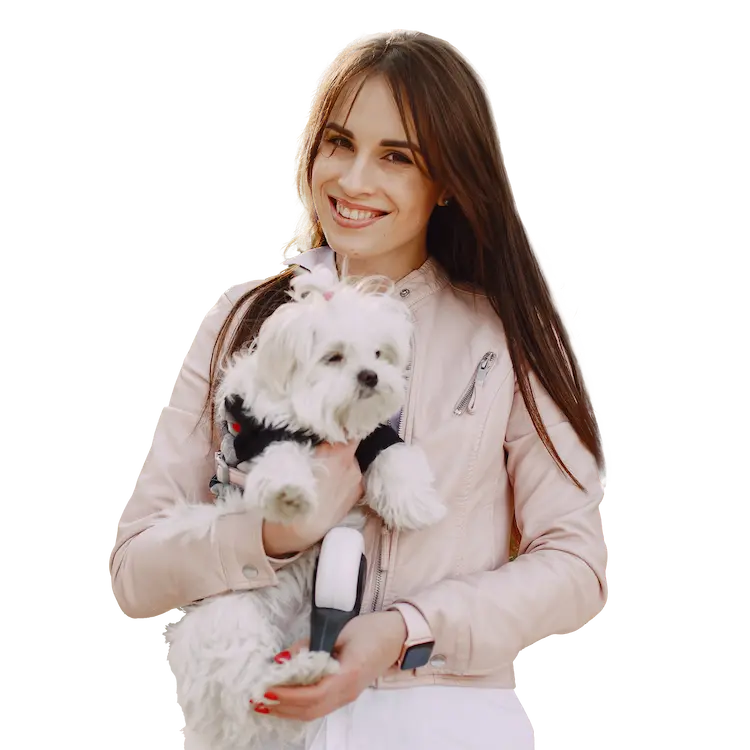 Jeune femme brune souriante tenant un bichon maltais en laisse, vêtue d’une veste rose pâle