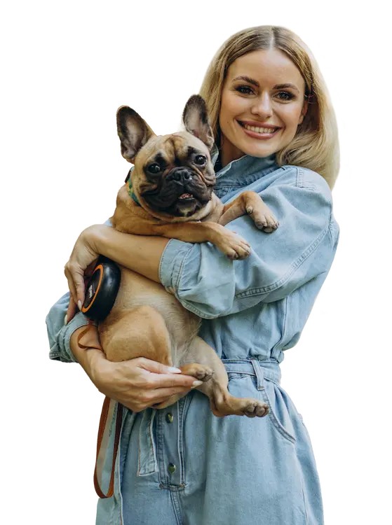 Femme blonde en combinaison en jean tenant un bouledogue français et souriant à l'appareil photo