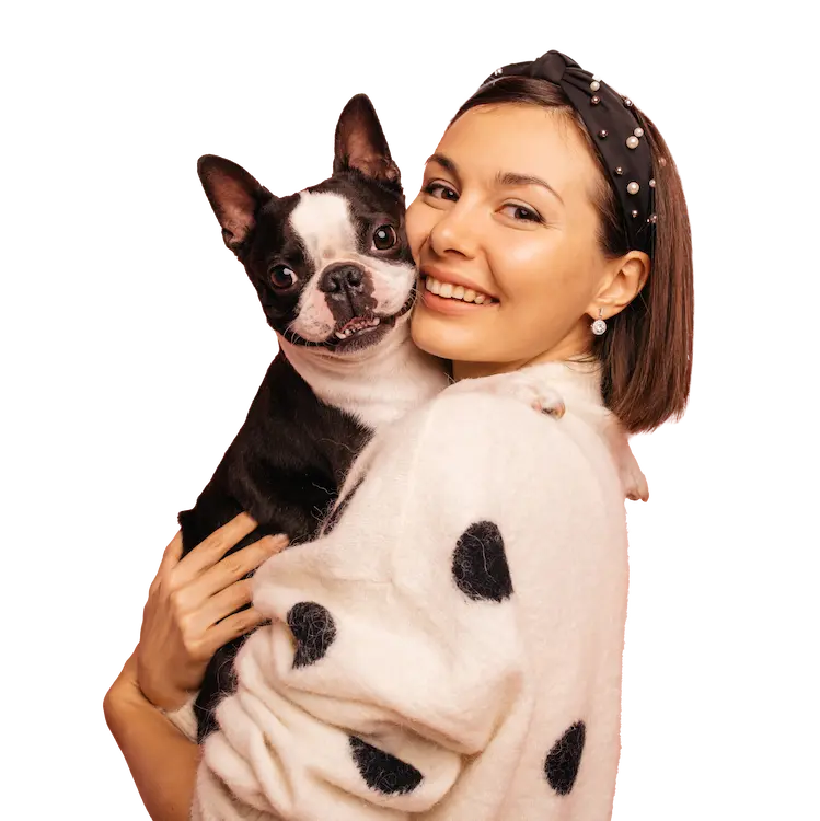 Jeune femme souriante tenant dans ses bras un Boston Terrier noir et blanc, montrant une belle complicité maître-chien