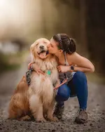 Éducatrice canine en train d’embrasser un Golden Retriever, illustrant la confiance et la complicité dans l’éducation positive du chien